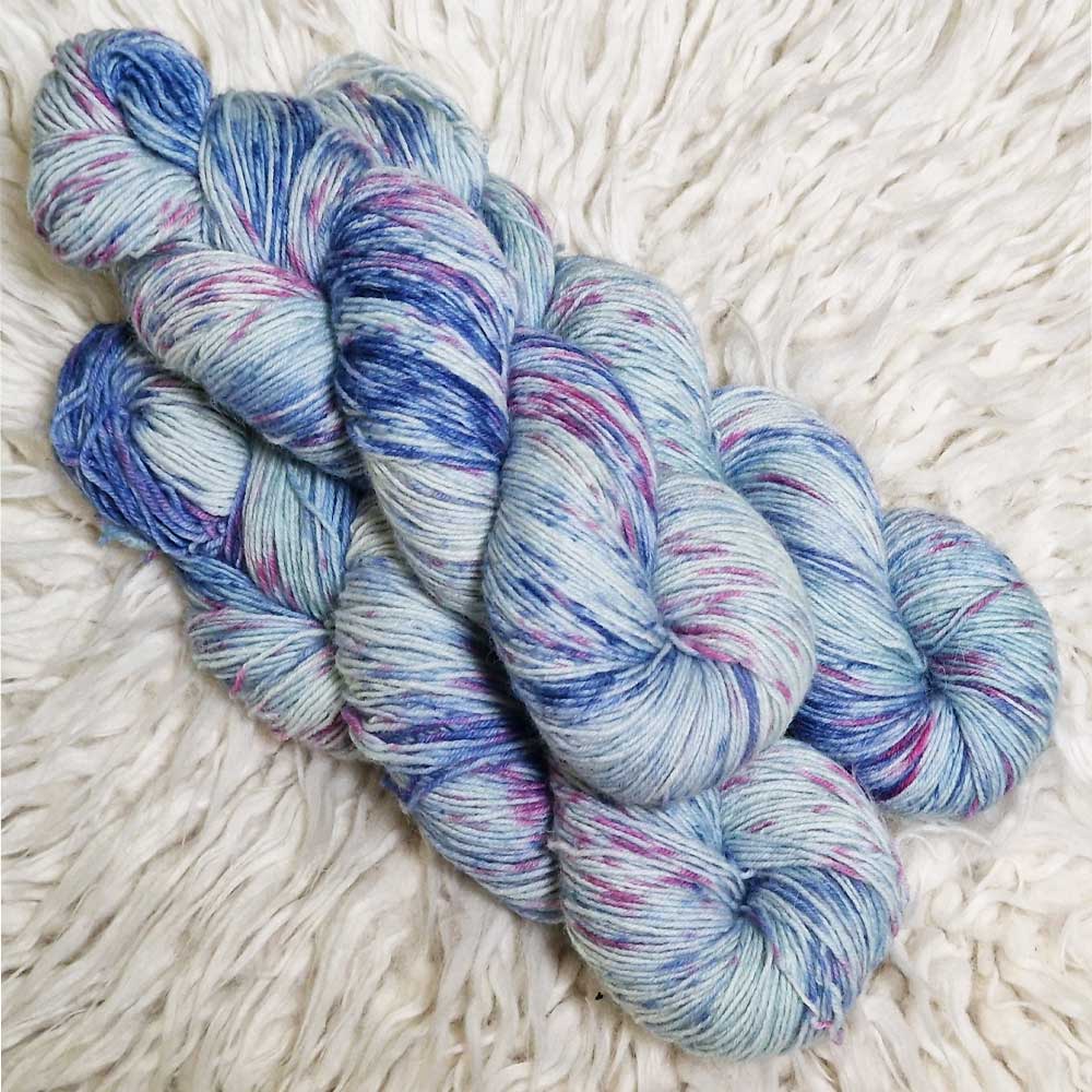 Weiche Sockengarne in Blau und Violett mit leichtem Melange-Effekt auf hellem Hintergrund.