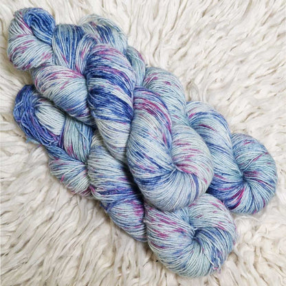 Weiche Sockengarne in Blau und Violett mit leichtem Melange-Effekt auf hellem Hintergrund.