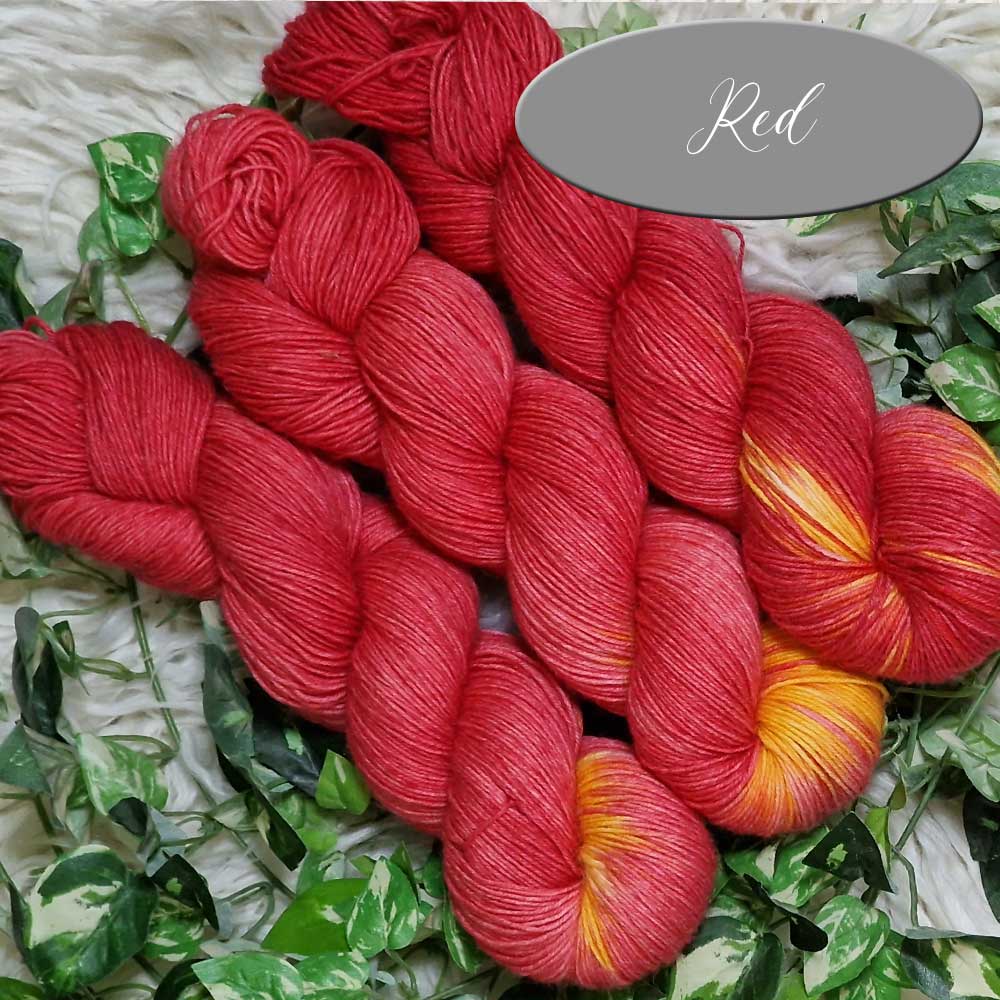 Rote, handgefärbte Wolle in locker gedrehten Strängen mit gelben Akzenten.